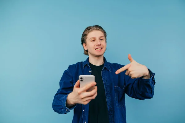 Positive Guy Shirt Holds Smartphone Points Finger Him Smile His — Fotografia de Stock