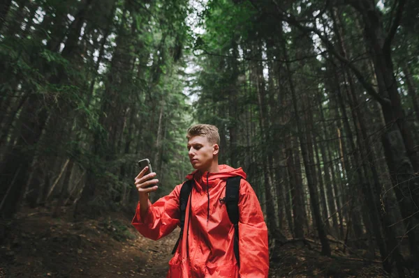 Jovem Bonito Grave Uma Capa Chuva Vermelha Usa Smartphone Uma — Fotografia de Stock