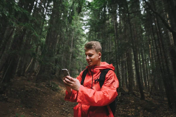 Усміхнений Молодий Чоловік Червоному Плащі Стоїть Лісовій Доріжці Горах Використовує — стокове фото