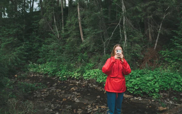 비옷을 여행객은 스마트폰으로 사진을 찍는다 아이는 풍경을 촬영하는 장면을 스마트폰으로 — 스톡 사진