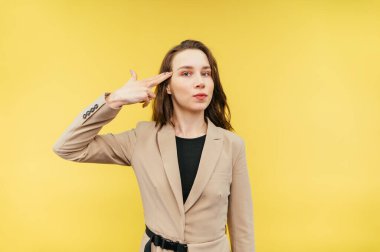 Bej ceketli bir kadın kameraya bakar ve ciddi bir yüzle parmağını başından vurur. Son teslim tarihi sırasında bir intihar jesti gösteriyor..