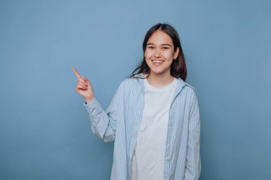 Gülümseyen kadın mavi arka planda yan tarafı işaret ediyor..