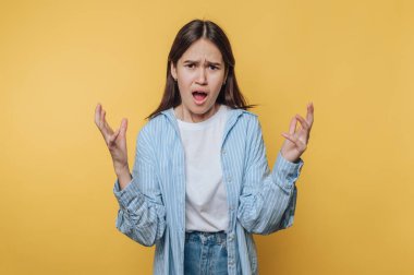 Young woman expressing frustration against yellow background.