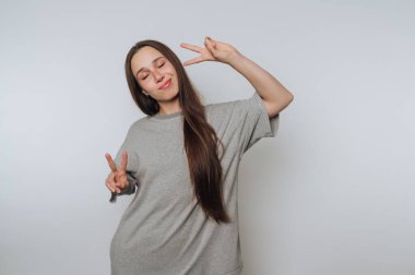 Woman in gray shirt making peace signs with both hands.