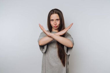 Woman making an X gesture with arms, neutral background