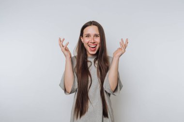 A young woman with long hair expressing excitement against a plain background.