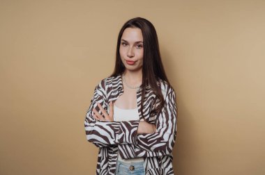 Woman in zebra print shirt with arms crossed against beige background.