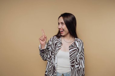 Woman in zebra print shirt pointing upwards against beige background