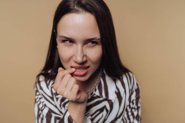 Woman biting her nails with a thoughtful expression.