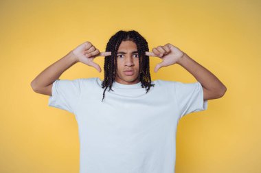 Person with braided hair posing against a yellow background.