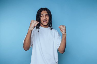 Örgülü saçlı genç adam yumruklarıyla kutlama yapıyor..