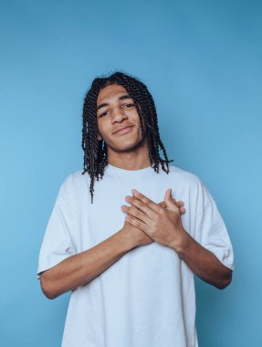 Mavi arka planda beyaz tişörtlü örgülü genç adam..