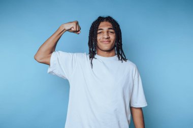 Young man with braided hair flexing his arm
