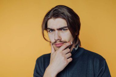 Man with thoughtful expression against orange background.