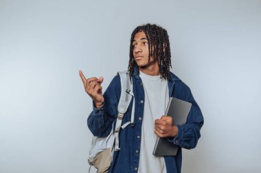 Young man with backpack and laptop gesturing with finger