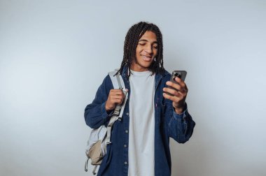 Young man with backpack looking at smartphone, smiling.