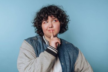 Person with curly hair pondering against blue background