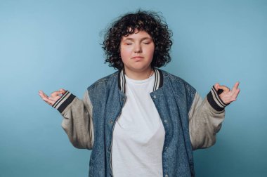 Person meditating with eyes closed against a blue background.