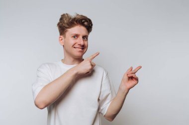 Young man in white shirt pointing with both hands