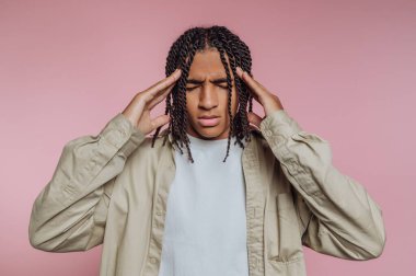 Genç adamın portresi hayal kırıklığını ve derin düşünceleri acı dolu bir ifadeyle ifade eder, pembe arka plana yaslanır.