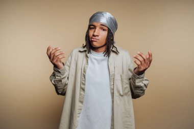 Düşünceli bir duruşu olan genç erkek figürü bej arka planda kararsızlık gösteriyor.