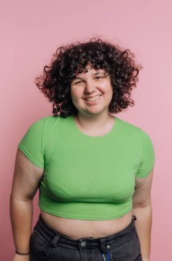 Yeşil ekinlerle süslenmiş neşeli bir kadının portresi pembe arka planda güvenle gülümsüyor.