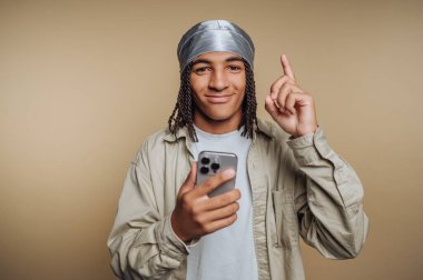 Elinde bir akıllı telefon, bej arka planda bir neşe ve bağlantı anı tutarken gümüş başlıklı genç bir adamın portresi
