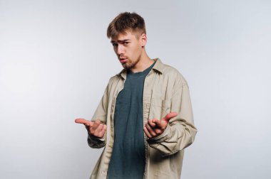 Genç bir adamın portresi neşeli bir poz veriyor, beyaz arka planda eğlenceli bir tutum sergiliyor.