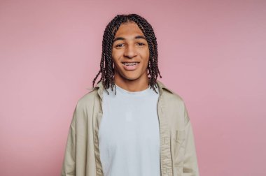 Genç adamın portresi kameraya sıcak bir şekilde gülümsüyor. Pembe arka planda cazibe ve dostluk yayıyor.