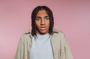 Genç adamın şaşı yüz ifadesinin portresi, pembe arka planda gerçek duygular gösteren şaşkınlığı yakalıyor.