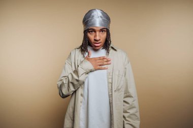 Şaşırdığını ve endişelendiğini ifade eden genç bir adamın portresi bej arka plandaki duygusal derinliğini vurguluyor.