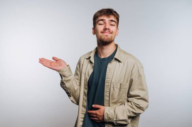 Genç bir adamın portresi özgüvenle kendini büyüleyici bir gülümseme ile sunuyor, beyaz arka planda gündelik, oyuncu bir tavır sergiliyor.