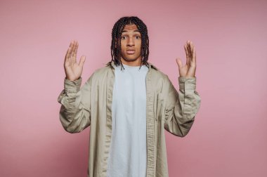 Şaşırmış genç adamın portresi kollarını kaldırır, pembe arka planda duygu ve nişanı gösterir.