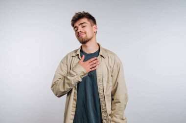 Genç bir adamın portresi sakince göğsünde duruyor, beyaz arka planda huzur ve sükunet hissi yayıyor.