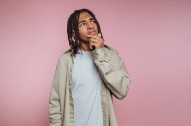 Düşünceli, genç bir adamın portresi. Pembe arka plana bakarken dalgın dalgın bakıyor.