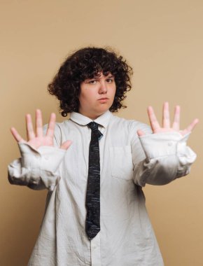 Beyaz gömlek ve bej arka planda kravat takan ve ellerini öne doğru uzatan genç bir kadının portresi.