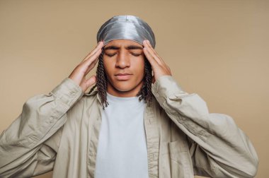 Genç bir adamın portresi başını tutar, derin düşüncelerini ya da derin düşüncelerini aktarır, bej arka plandaki karmaşık duyguları işlermiş gibi.