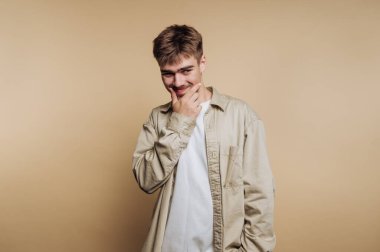 Genç adamın portresi, bej arka planda muzip bir gülümsemeyle neşeli bir tavır sergiliyor.