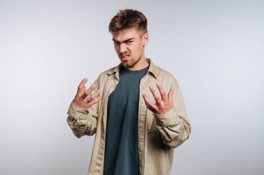 Genç bir adam evde dikiliyor, gözle görülür şekilde hayal kırıklığına uğramış. Elleri havada ve yüz ifadesi rahatsızlık ve inançsızlığın karışımını gösteriyor. Arkaplan sade bir açık renk.