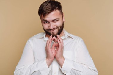 Bir adam küstah bir sırıtış ve neşeli bir el hareketi sergiler, kendine güveni ve çekiciliği yayar. Beyaz bir gömlek giyiyor, anı neşeli ve neşeli kılıyor..