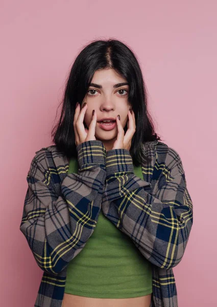 Pembe arka plana karşı şaşırmış genç bir kadın.