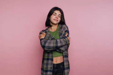 Pembe arka planda kendine sarılan bir kadın..