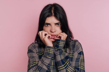 Pembe arka plana karşı endişeli bir ifadesi olan genç kadın..