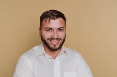 Bej arka planda beyaz gömlekli, gülümseyen adam..