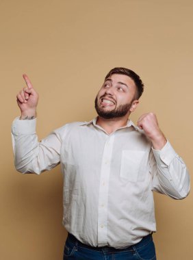 Beyaz tişörtlü bir adam neşeli bir ifadeyle yukarı bakıyor..