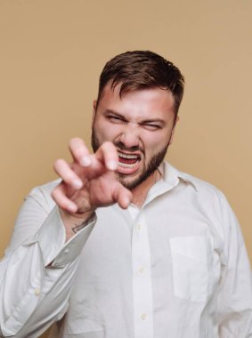 Beyaz gömlekli adam sert bir ifadeyle pençe hareketi yapıyor..