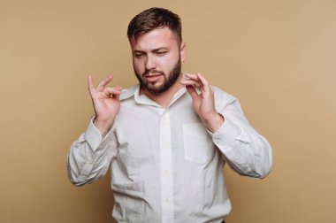 Beyaz gömlekli bir adam ellerini bej arka planda gezdiriyor..