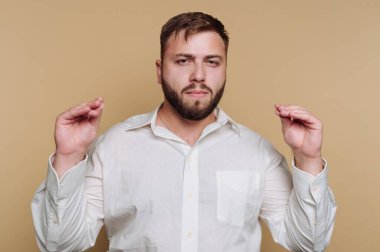 Beyaz gömlekli, elleri bej arka planda hareket eden bir adam..