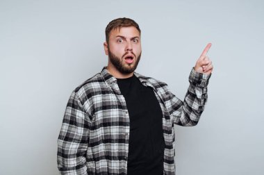 Ekose gömlekli, arka planda yukarıya bakan şaşırmış bir adam..