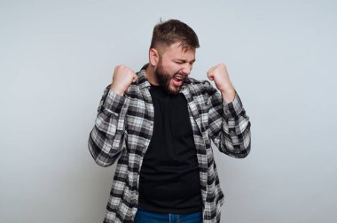 Ekose gömlekli bir adam yumruklarını sıkarak kutluyor..